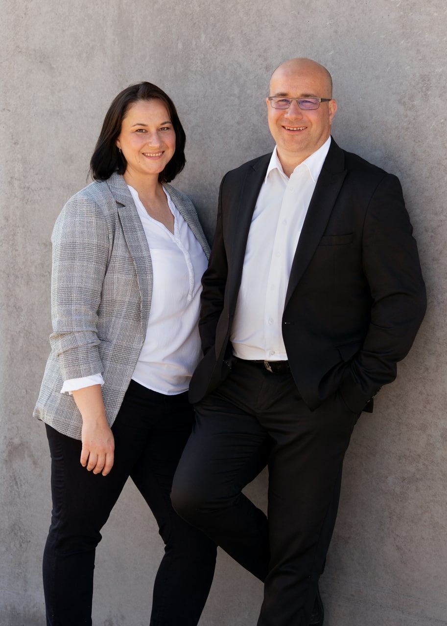 Angela und Zeljko gemeinsam vor grauem Hintergrund